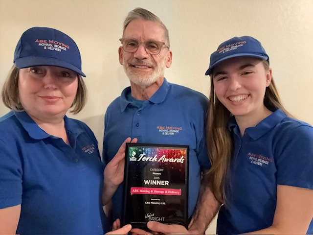 ABE Moving - Family holding Torch Award winner plaque from the Better Business Bureau